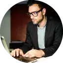 Professional male writer wearing glasses, typing on a laptop represents native UK assignment expert providing accurate, subject-specific, plagiarism-free help with 24x7 student support